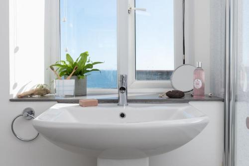 a white sink in a bathroom with a window at Rosevean in Marazion