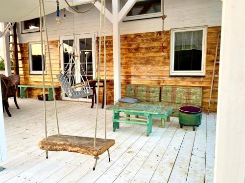 a porch with a swing and a table and a bench at Bohemian Eco lodge át lake Balaton in Kisapáti