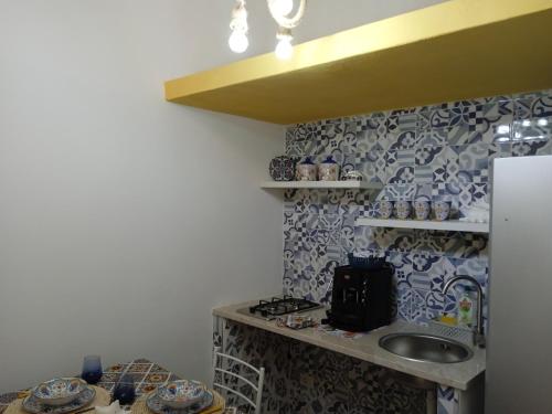 a kitchen with a sink and a counter with a shelf at Mary Gery's Rooms in Castellammare del Golfo