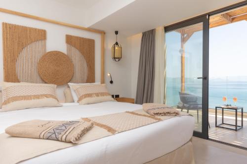 a bedroom with a large bed with a view of the ocean at Cabana Blu Hotel & Suites in Kardamaina