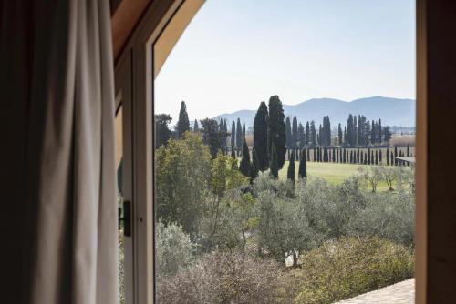 a window with a view of a field and trees at Guadalupe Tuscany Resort in Braccagni