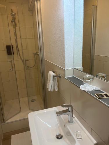 ein Bad mit einem Waschbecken und einer Dusche mit einem Spiegel in der Unterkunft Gasthof Wulf in Bremen