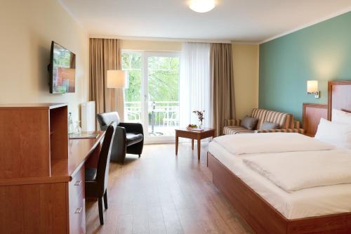 Habitación de hotel con cama y escritorio en R&R Strandhotel Baabe en Baabe