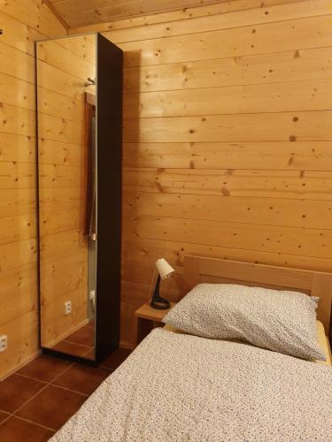 a bedroom with a bed and a wooden wall at Sport-hotel Šibeniční vrch in Mnichovice