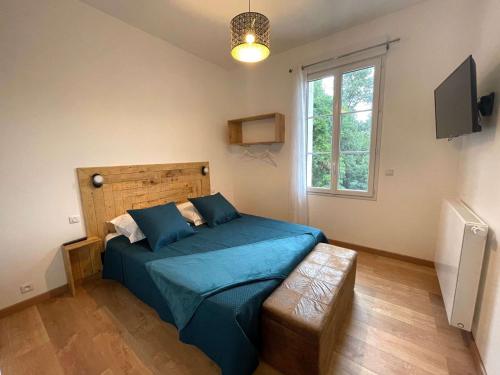 1 dormitorio con cama con sábanas azules y ventana en Havre de paix - Chambres d'hôtes en La Sauve-Majeure