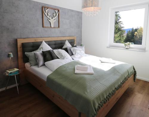 1 dormitorio con 1 cama con manta verde y ventana en Design-Ferienhaus "auf der Schanz" mit privater Sauna - Todtnau-Muggenbrunn, Feldberg im Schwarzwald en Muggenbrunn