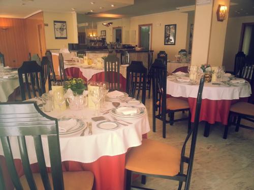 uma sala de jantar com mesas e cadeiras com mesas brancas em Hotel La Brañina em Villablino