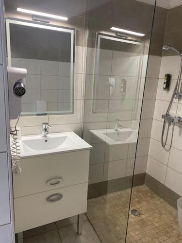 a bathroom with a sink and a shower at LOGIS Hôtel La Chaumière in Marseillan