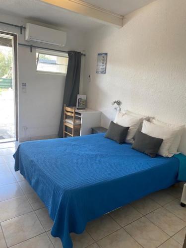 a bedroom with a blue bed with a blue blanket at LOGIS Hôtel La Chaumière in Marseillan