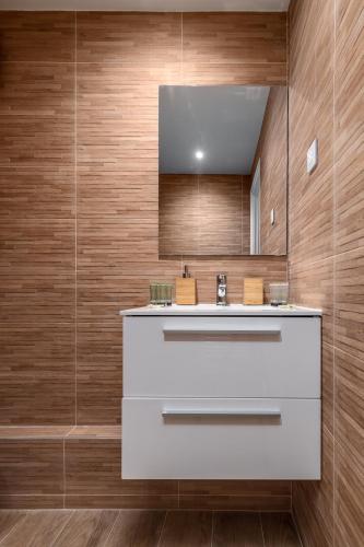 La salle de bains est pourvue d'un lavabo blanc et de murs en bois. dans l'établissement Cosy flat in Saint-Germain des près, à Paris