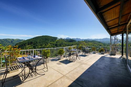 a patio with tables and chairs on a balcony at Morning Dew Boutique Hotel Ella in Ella