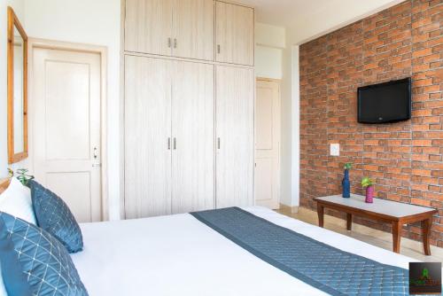 a bedroom with a bed and a brick wall at Exotic Stays I The Kasauli Western Uphills I Vacations I Family Groups & Events I Forest Treks I Memories I Serviced Apartments I Kasauli in Kasauli