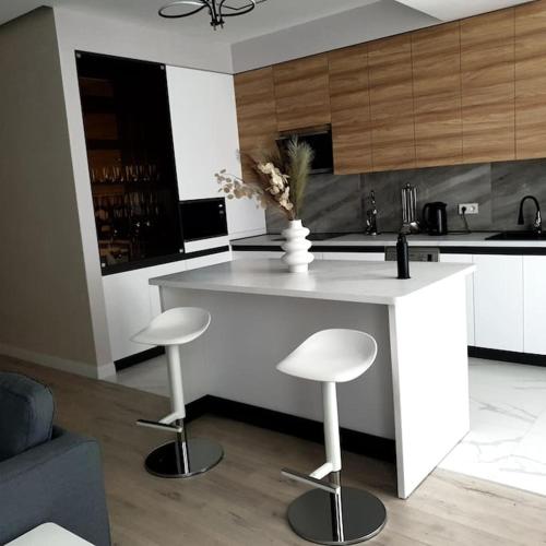 a kitchen with a white island with two stools at Lovely 1-bedroom rental unit in downtown in Dushanbe