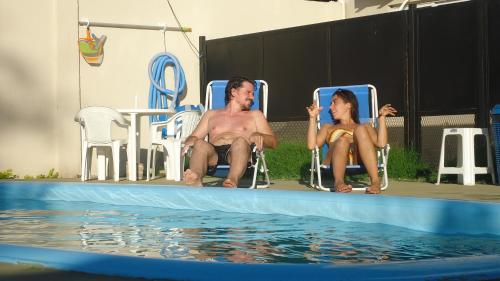 a man and woman sitting in lawn chairs next to a swimming pool at Atalaya in Colón