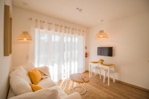 een woonkamer met een witte bank en een tafel bij 188 Apartments - Buganvília - pool and balcony in Cascais