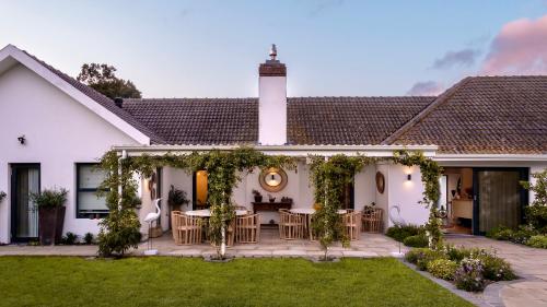 a white house with a patio with tables and chairs at The Dongola Guesthouse in Cape Town