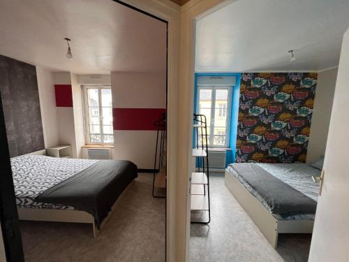 une chambre avec deux lits et un miroir dans l'établissement T3 50m2 Lumineux proche mairie - plein centre, à Carhaix-Plouguer