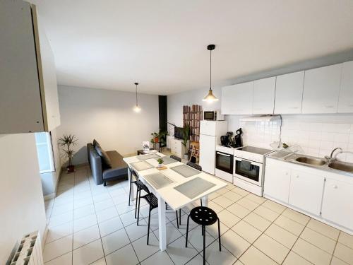 a kitchen with white cabinets and a table with chairs at T3 50m2 Lumineux proche mairie - plein centre in Carhaix-Plouguer