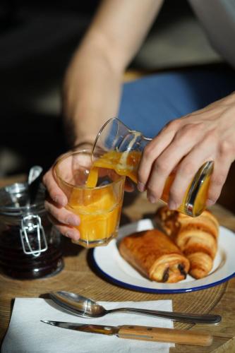 eine Person gießt Orangensaft in ein Glas mit einem Teller Essen in der Unterkunft travelski home select - Résidence & Hostel Yoonly & Friends in Risoul