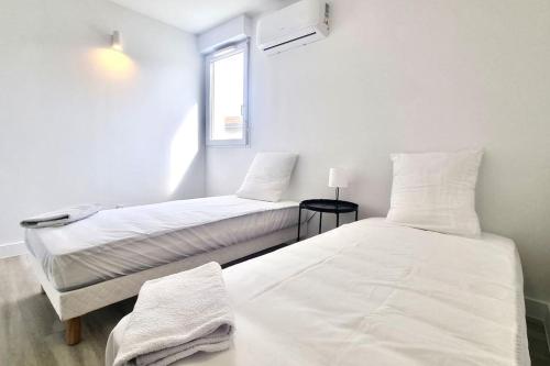 2 łóżka w białym pokoju z oknem w obiekcie Résidence Anthérieu - Appartements neufs tout confort w mieście Frontignan