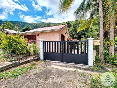 a gate in front of a house with a palm tree at Kaz'A Olymp - classé 3 étoiles - Maison de vacances à l'Entre-Deux in LʼEntre-Deux