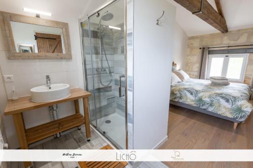 een badkamer met een douche, een wastafel en een bed bij L'Epicure in Langoiran