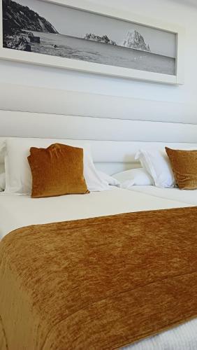 a white bed with brown blankets and pillows at Hotel Argos Ibiza in Talamanca
