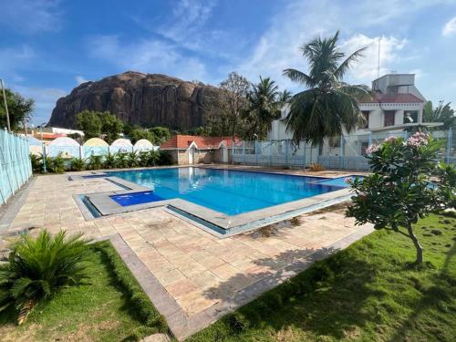 a swimming pool in a backyard with a mountain in the background at Alps Residency in Madurai