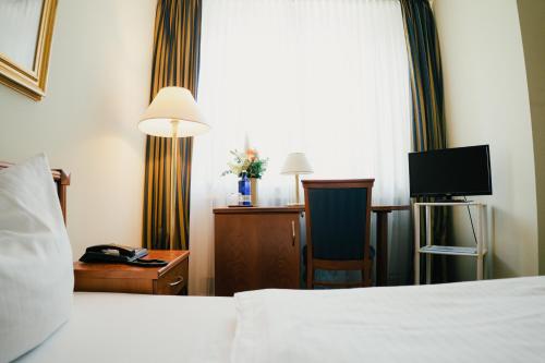 a hotel room with a bed and a desk and a television at Altstadt Hotel St. Georg in Düsseldorf
