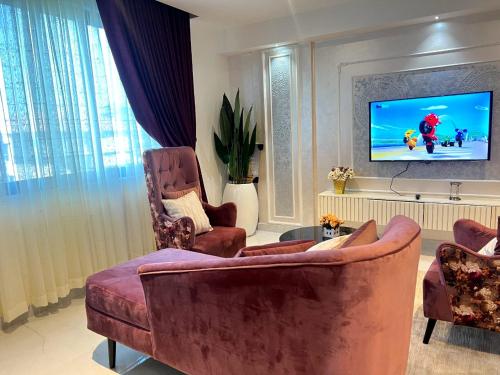 a living room with two chairs and a flat screen tv at Iconic Tower Pink Room in Lagos