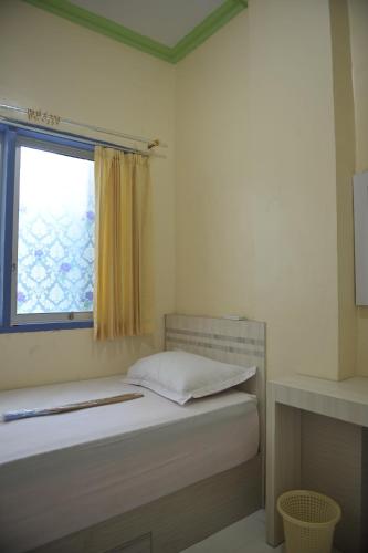 een kleine slaapkamer met een bed en een raam bij Penginapan AIRA in Palu