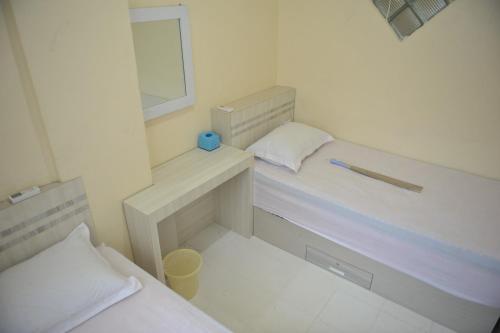 a small room with two beds and a mirror at Penginapan AIRA in Palu