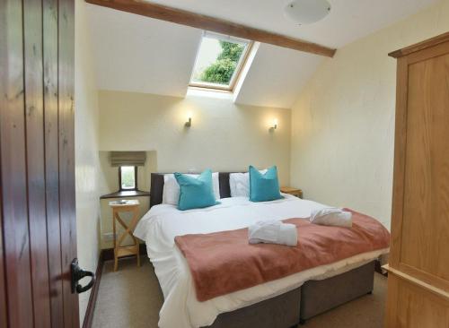 a bedroom with a bed with blue pillows and a window at Elliott Cottage in Buxton