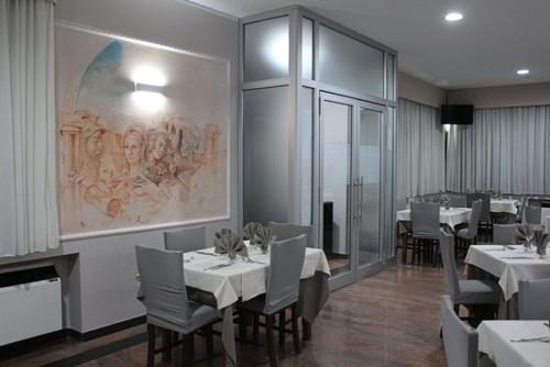 a dining room with white tables and chairs and a painting at Prestige in Trevico