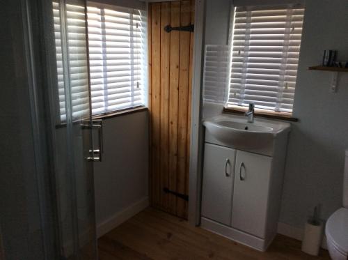 a bathroom with a sink and a window with shutters at Tremeer Cottage in Upper Beeding