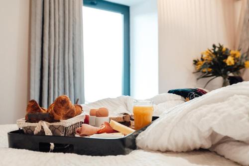 - un plateau de nourriture et de jus d'orange sur le lit dans l'établissement Urban Style LES FLEURINES, à Villefranche-de-Rouergue