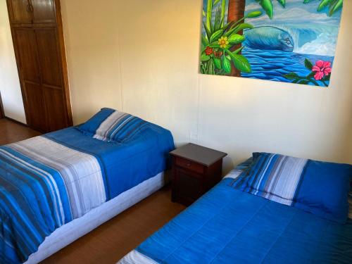 a bedroom with two beds and a painting on the wall at Hostel El Bajo in Iquique