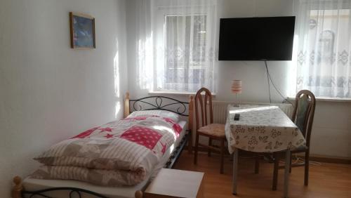 1 dormitorio con cama, mesa y TV en Wendler`s Haus, en Meuselwitz