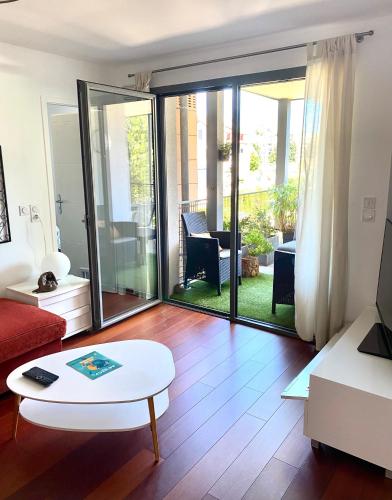 salon z przesuwnymi szklanymi drzwiami prowadzącymi na patio w obiekcie Appart Cosy proche du lac avec terrasse w Annecy