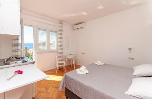 Schlafzimmer mit einem Bett, einem Waschbecken und einem Tisch in der Unterkunft Apartments and Rooms Nikola in Omiš