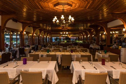 a restaurant with white tables and chairs and a chandelier at Yucelen Hotel in Akyaka