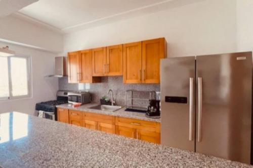 a kitchen with wooden cabinets and a stainless steel refrigerator at Chic and Relax Apartamento Juan Dolio in San Pedro de Macorís