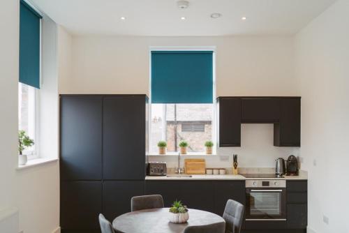 a kitchen with black cabinets and a table with chairs at Apartment 8 2 bedrooms, sleeps x 6 in York