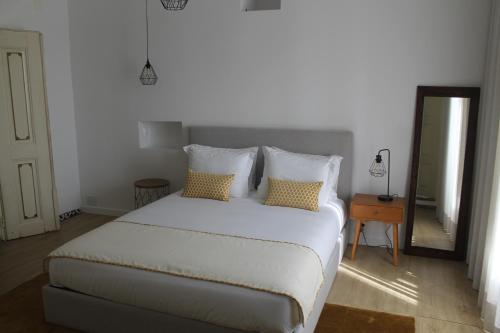 a bedroom with a white bed and a mirror at AltoCanto in Coimbra