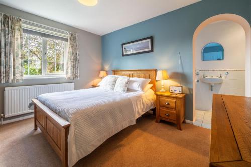 a bedroom with a bed and a bathroom with a sink at Field End in Westleton