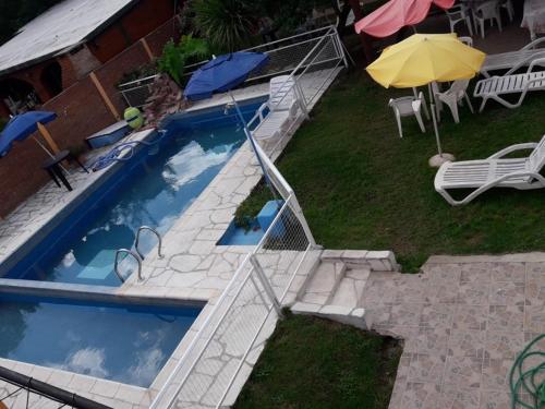 a swimming pool with an umbrella next to a yard at Posada Los Arcos in Villa Cura Brochero