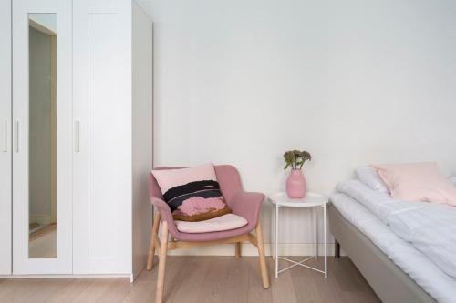 ヘルシンキにある2ndhomes Cozy Studio in the City Centerのベッドルーム1室(ピンクの椅子付)