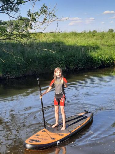 a young girl standing on a paddle board in the water at Ferienwohnungen Bekperle in Bekdorf