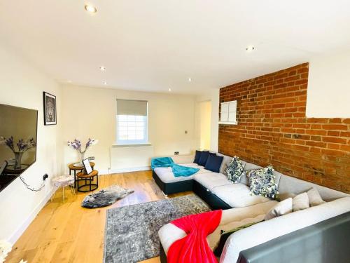 a living room with a couch and a brick wall at 75 Weavers Townhouse in Norwich