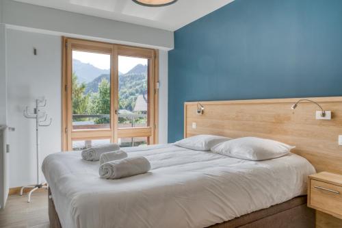 una camera da letto con un grande letto con pareti blu e una finestra di IMMOBILIER DE MONTAGNE - LA COLLECTION - Beaulieu a Saint-Gervais-les-Bains